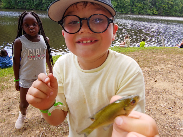 A boy holding a small fish.