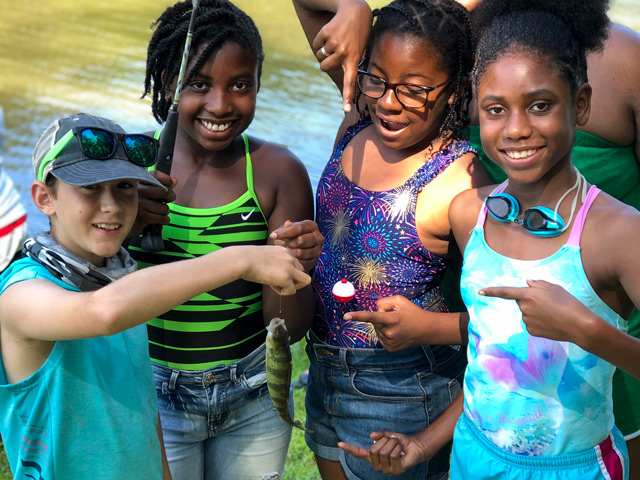 Group of children holding up a fish they caught.